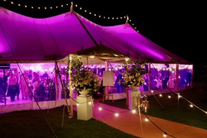 Dining at night inside a traditional pole wedding marquee