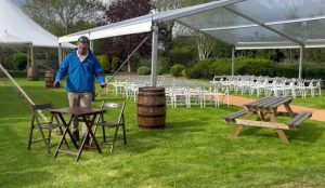 Ceremony tent featuring wooden barrels, white garden furniture and wooden benches