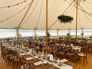Wedding interior with rows of rustic trestle tables and crossback chairs